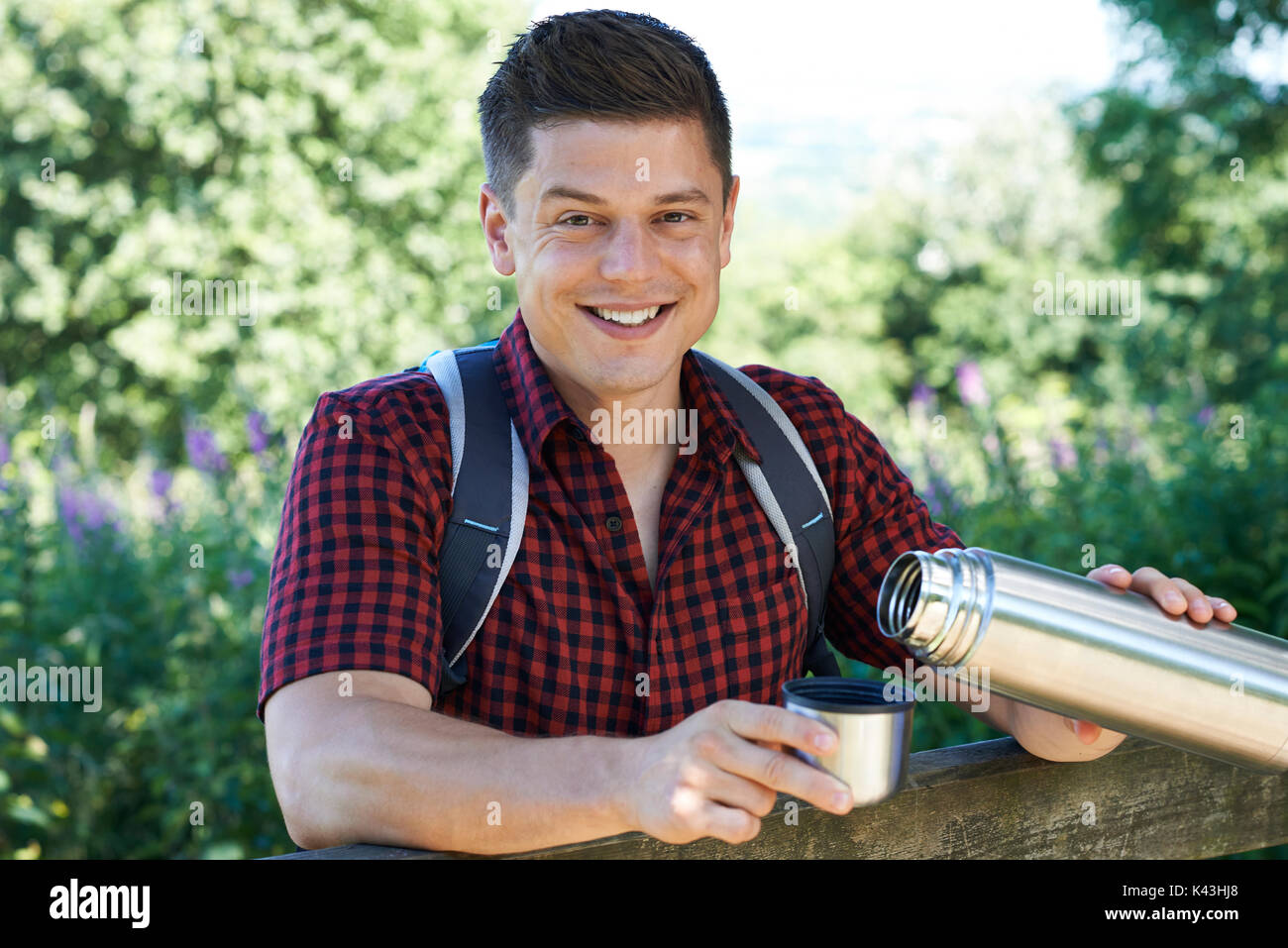 Portrait Of Man Pouring Hot Drink From Flask On Walk Stock Photo
