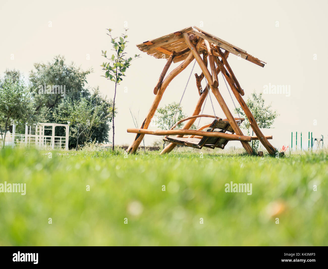 Brown wooden swinging bench in the garden Stock Photo - Alamy