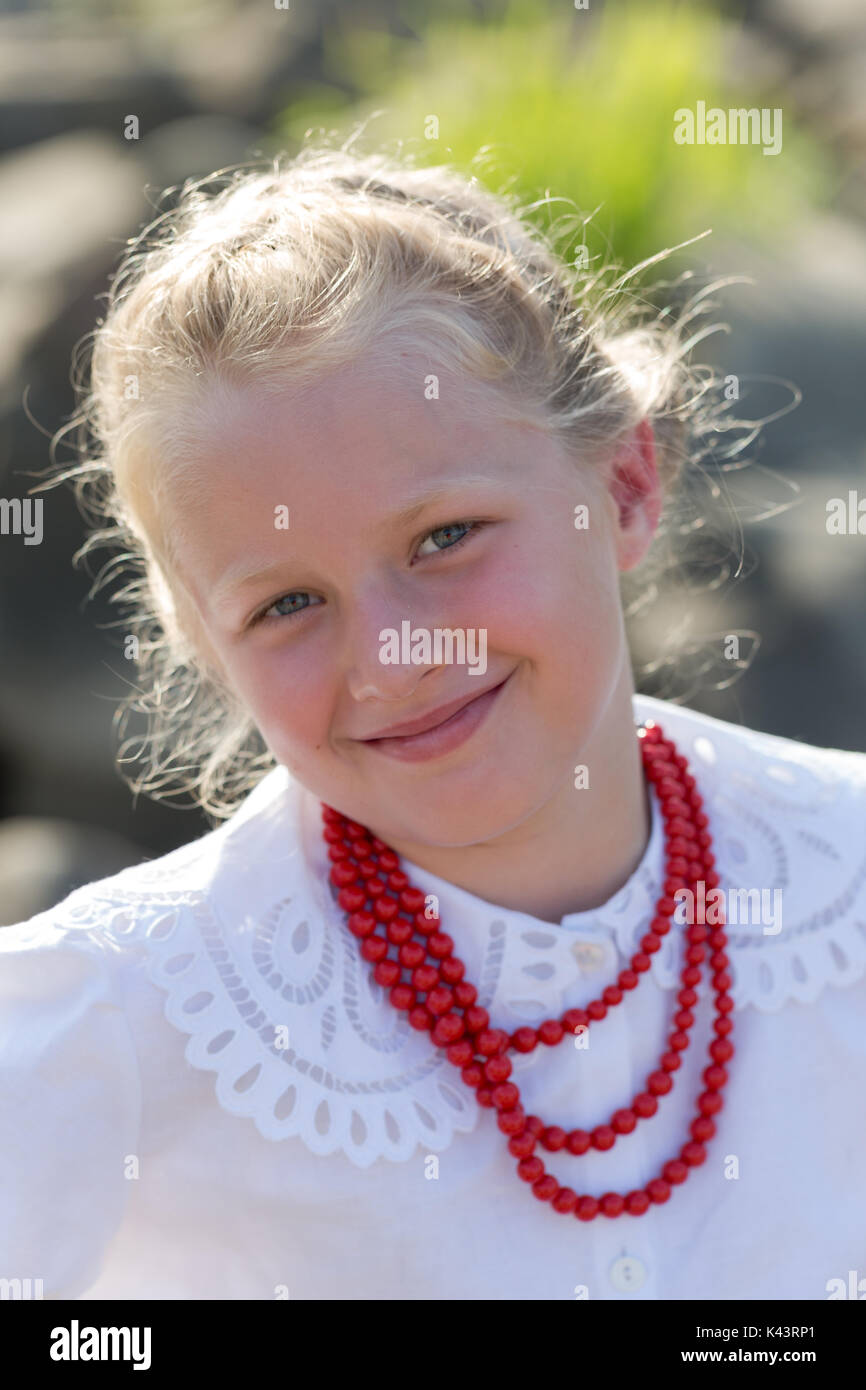 Child blonde girl in formal white shirt and red necklace portrait. Vertical crop Stock Photo