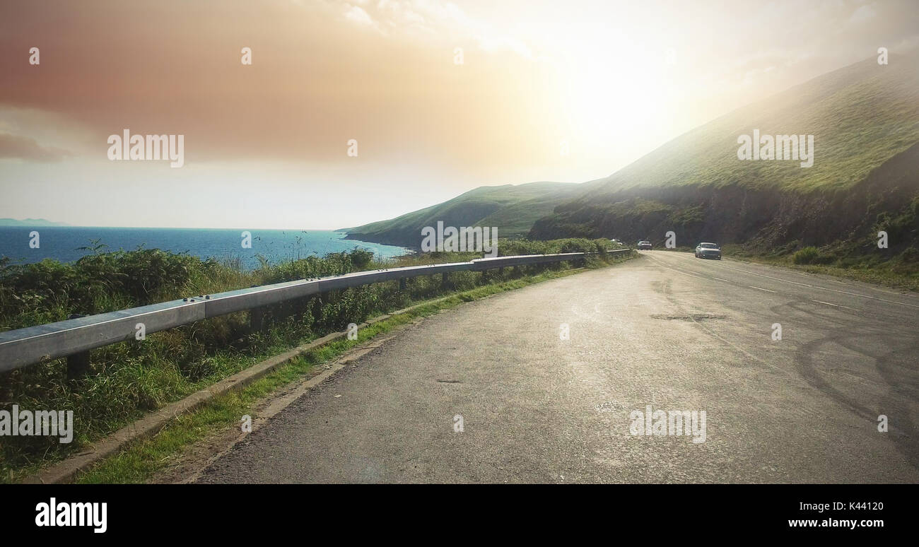 Road by sea against sky on bright sunny day Stock Photo