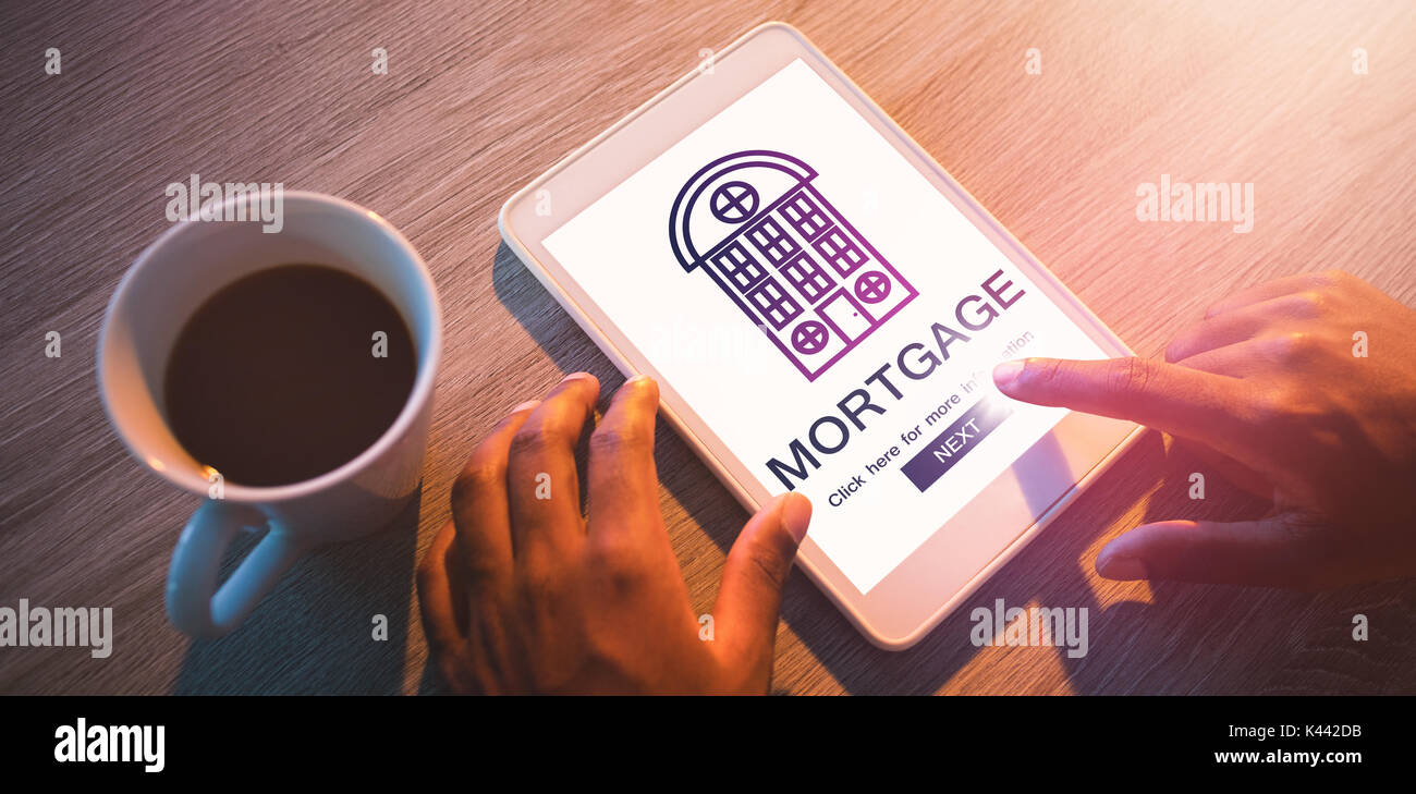 Composite image of mortgage text with icon against cropped hands of buisnessman using digital tablet at desk Stock Photo