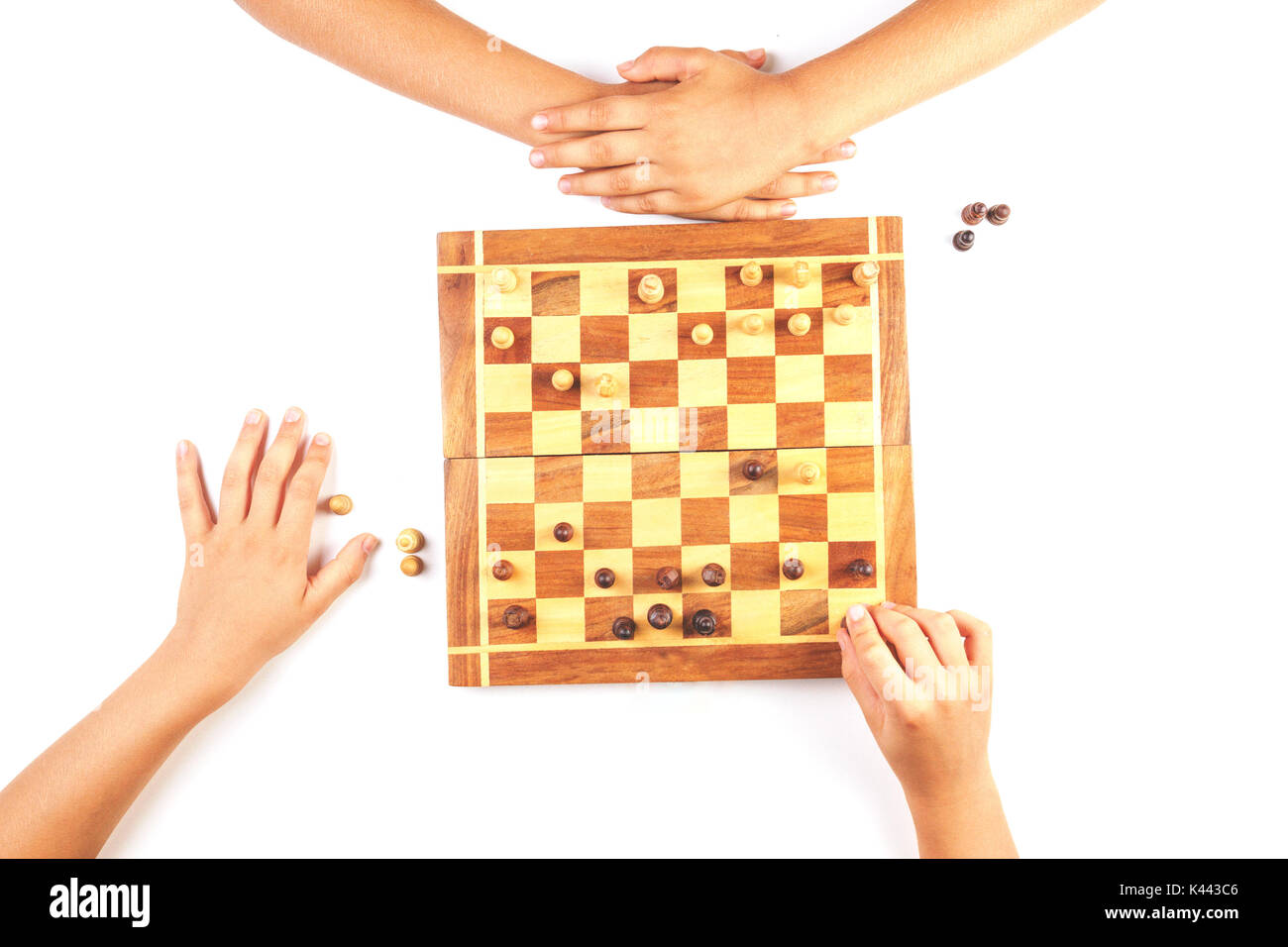 Chess board with chess pieces and a playing kids hand. Stock Photo