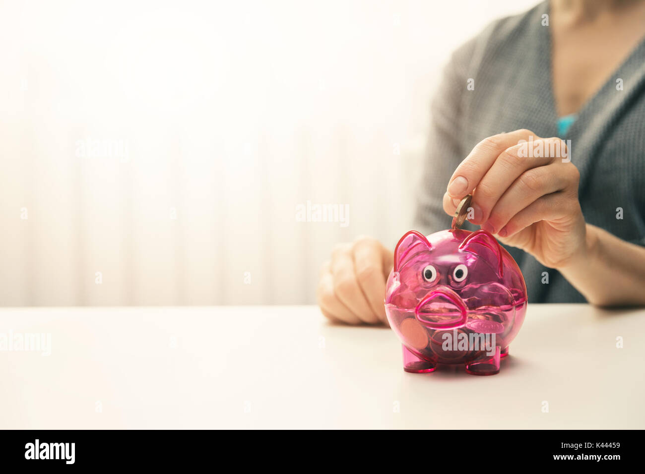 woman putting coin in piggy bank. copy space Stock Photo
