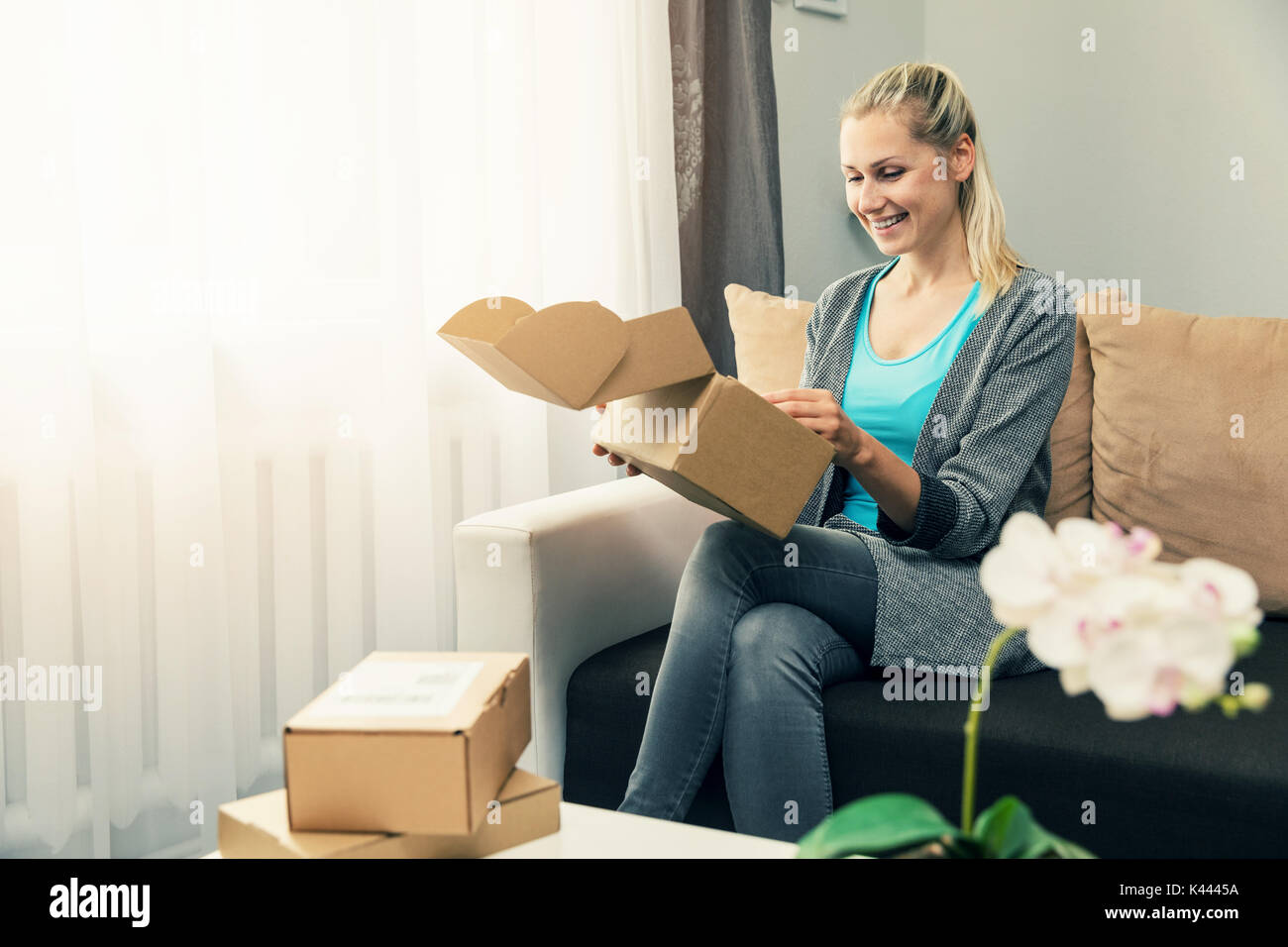 home delivery - smiling young woman opening cardboard box Stock Photo