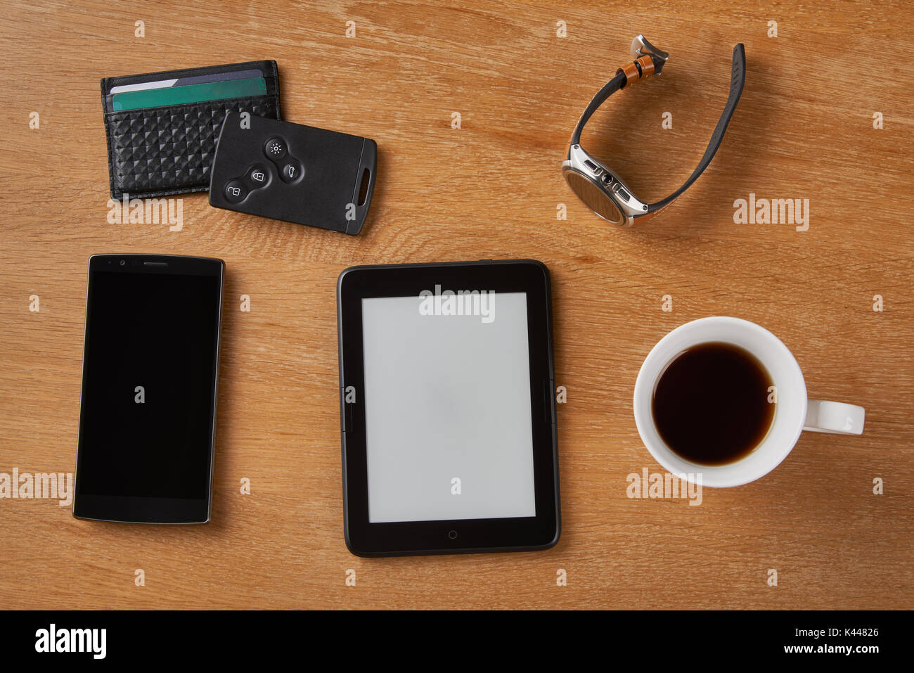 E-book device with Smart key, card wallet, smart watch, smart phone and a cup of coffee on a wooden table. Stock Photo