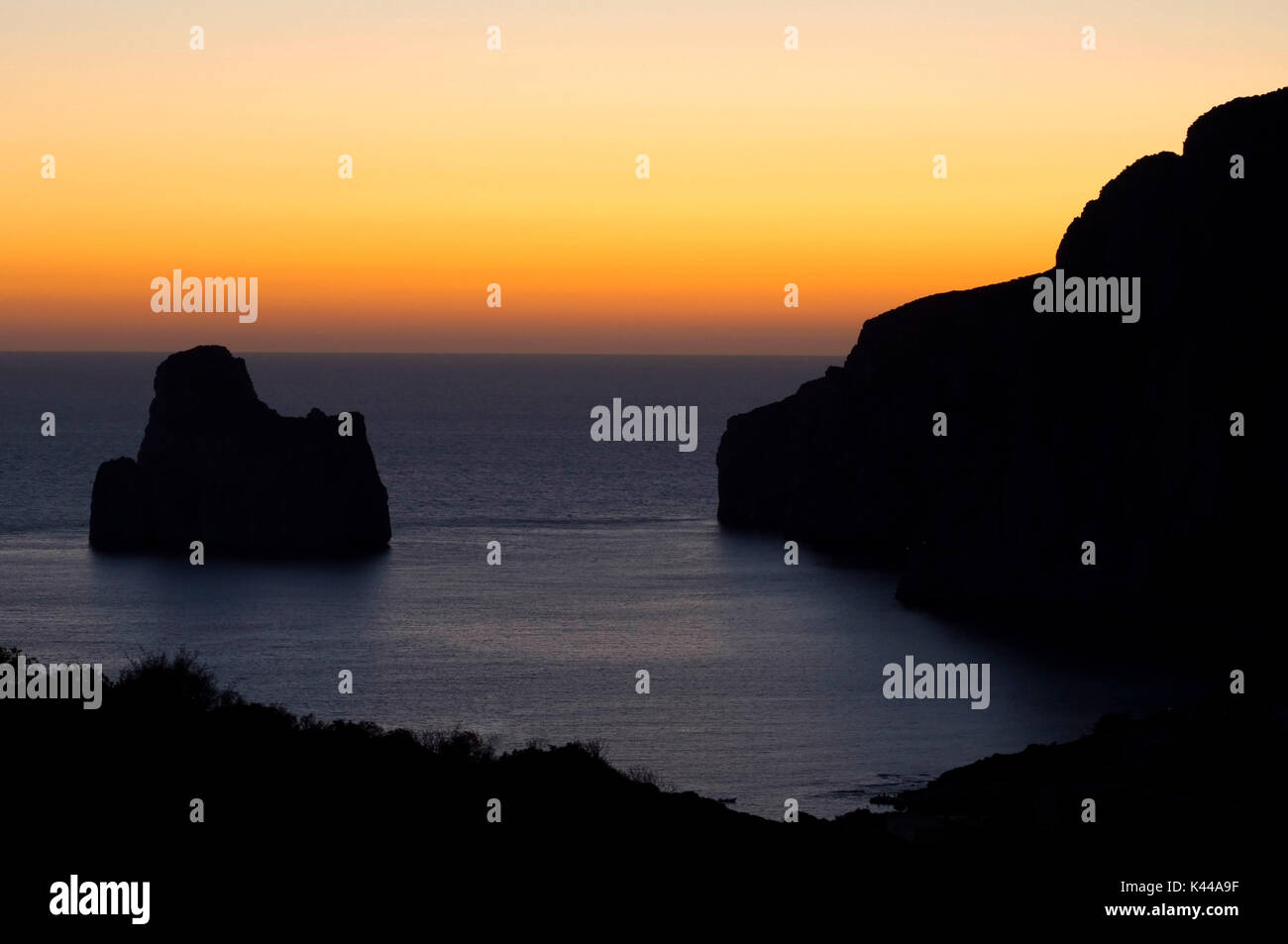 Europe, Italy, Sardinia region, Iglesias district, Masua village. The island of Pan di Zucchero in silhouette at dusk. Stock Photo