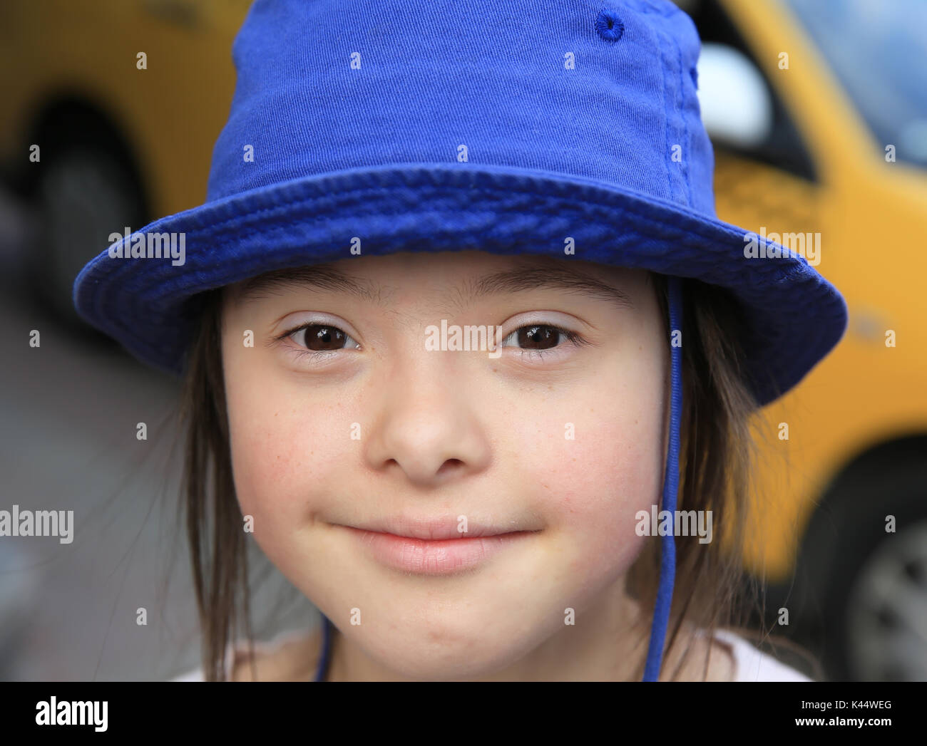 Cute smiling down syndrome girl on the background of taxi Stock Photo