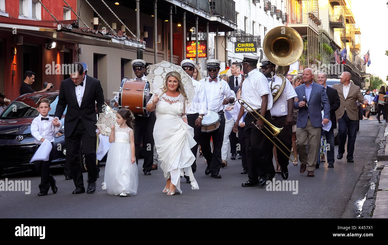 Bride and groom lead a marching band and wedding parade down the streets of the historic French Quarter in New Orleans Stock Photo