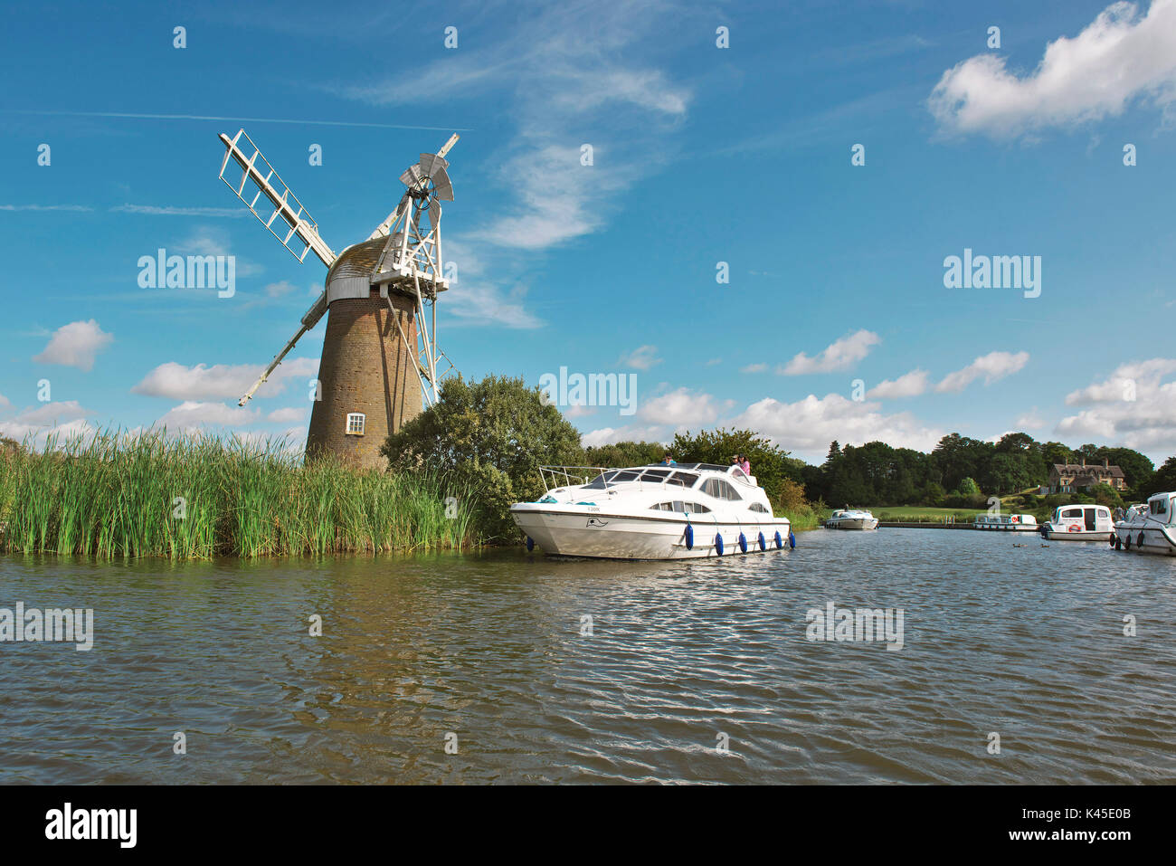 Lovely Broads cruiser on the river ant at How Hill in front of Mill on a bright summers day Stock Photo