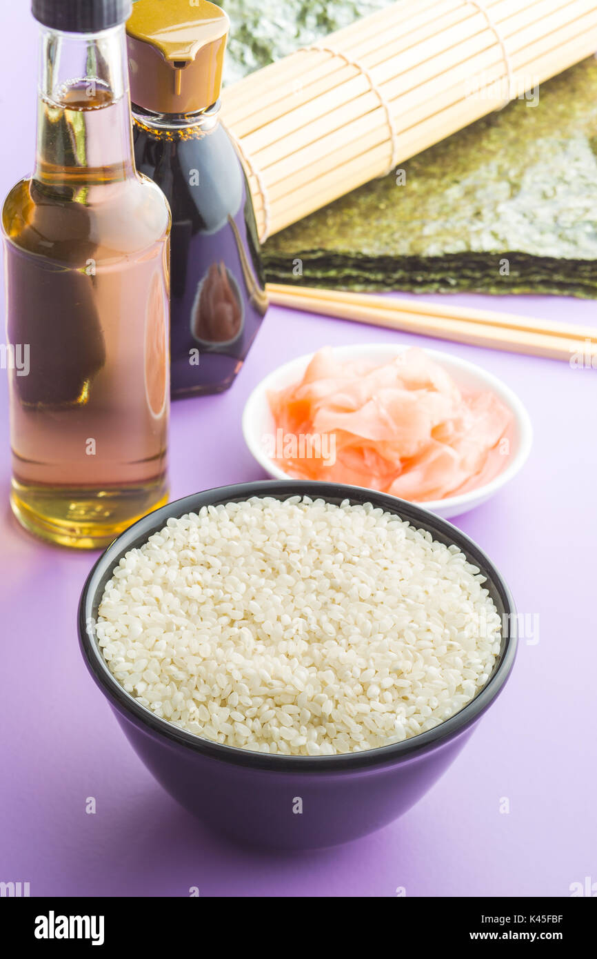 The sushi ingredients on purple table. Rice, ginger, soy sauce, vinegar and nori sheets. Stock Photo