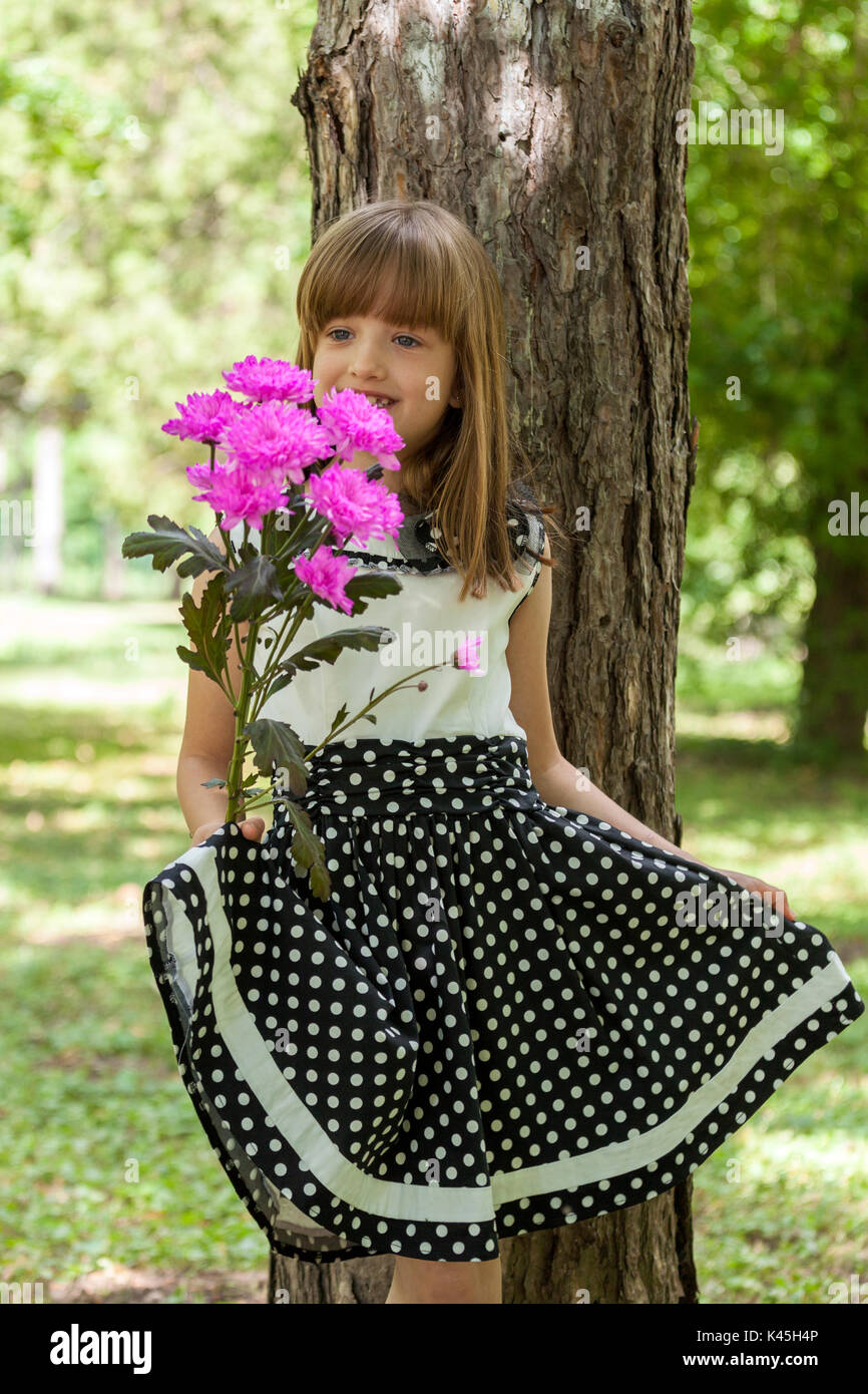 Portrait of a beautiful little girl with big blue eyes in a dress while ...