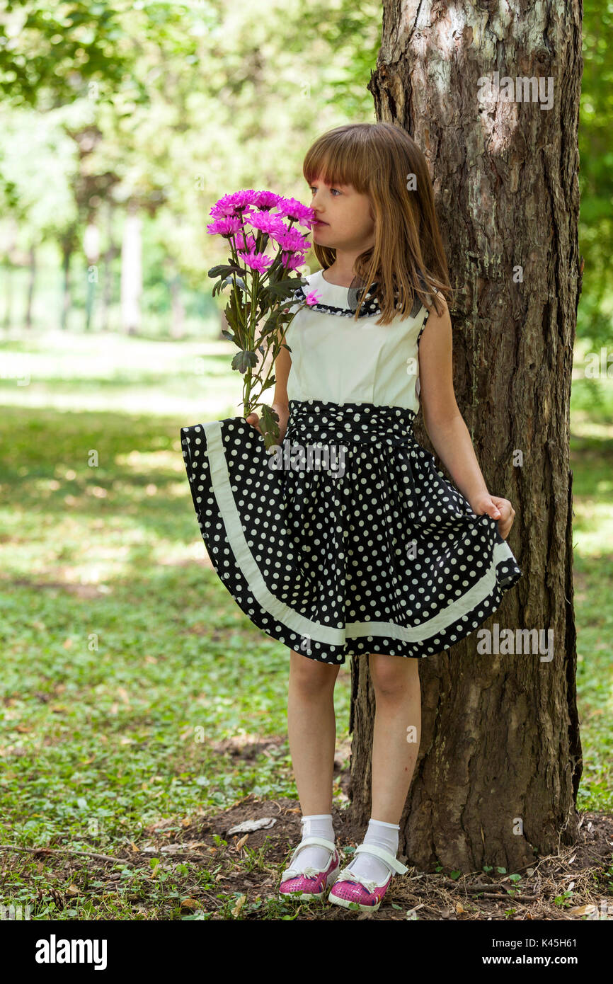 Portrait of a beautiful little girl with big blue eyes in a dress while ...