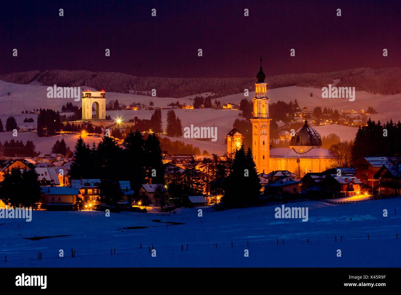 Town, Altopiano of Asiago, Province of Vicenza, Veneto, Italy. Military monument and Cathedral in winter landscape. Stock Photo