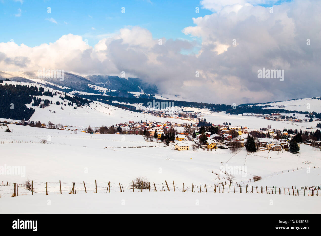 Town, Altopiano of Asiago, Province of Vicenza, Veneto, Italy. Coloured houses in winter landscape. Stock Photo