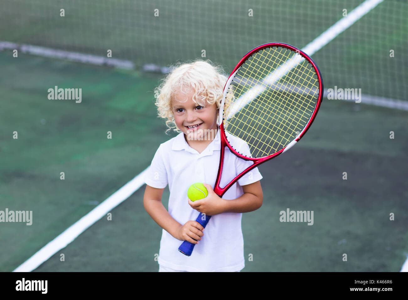 Child playing tennis on outdoor court. Little boy with tennis racket ...