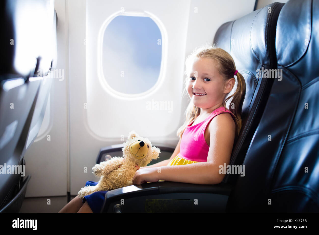 Child in airplane. Kid in air plane sitting in window seat. Flight