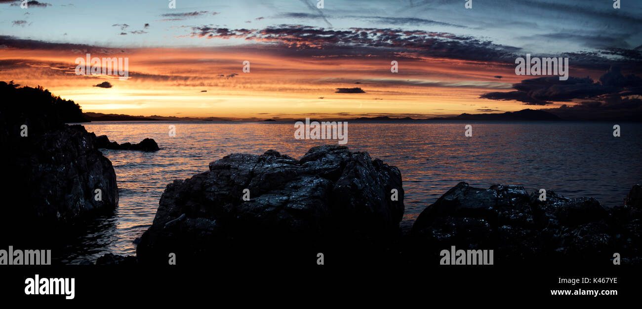 Beautiful dramatic panoramic sunset sky scenery of rocks on the Pacific ocean coast in Nanaimo, Vancouver Island, BC, Canada. Stock Photo