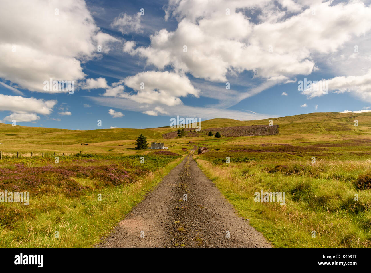 STIRLING, UNITED KINGDOM - AUGUST 9, 2017 - A dirt road near the Cairngorms National Park in Scotland with a house alone in the middle of a field. Stock Photo