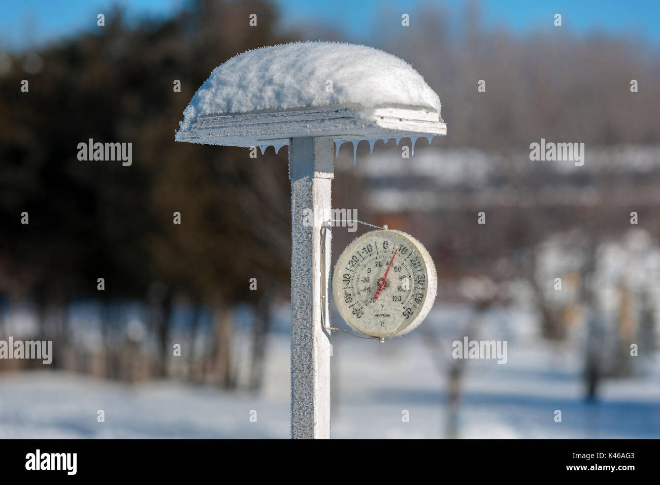 Frost covered circuler thermometer on white post Stock Photo