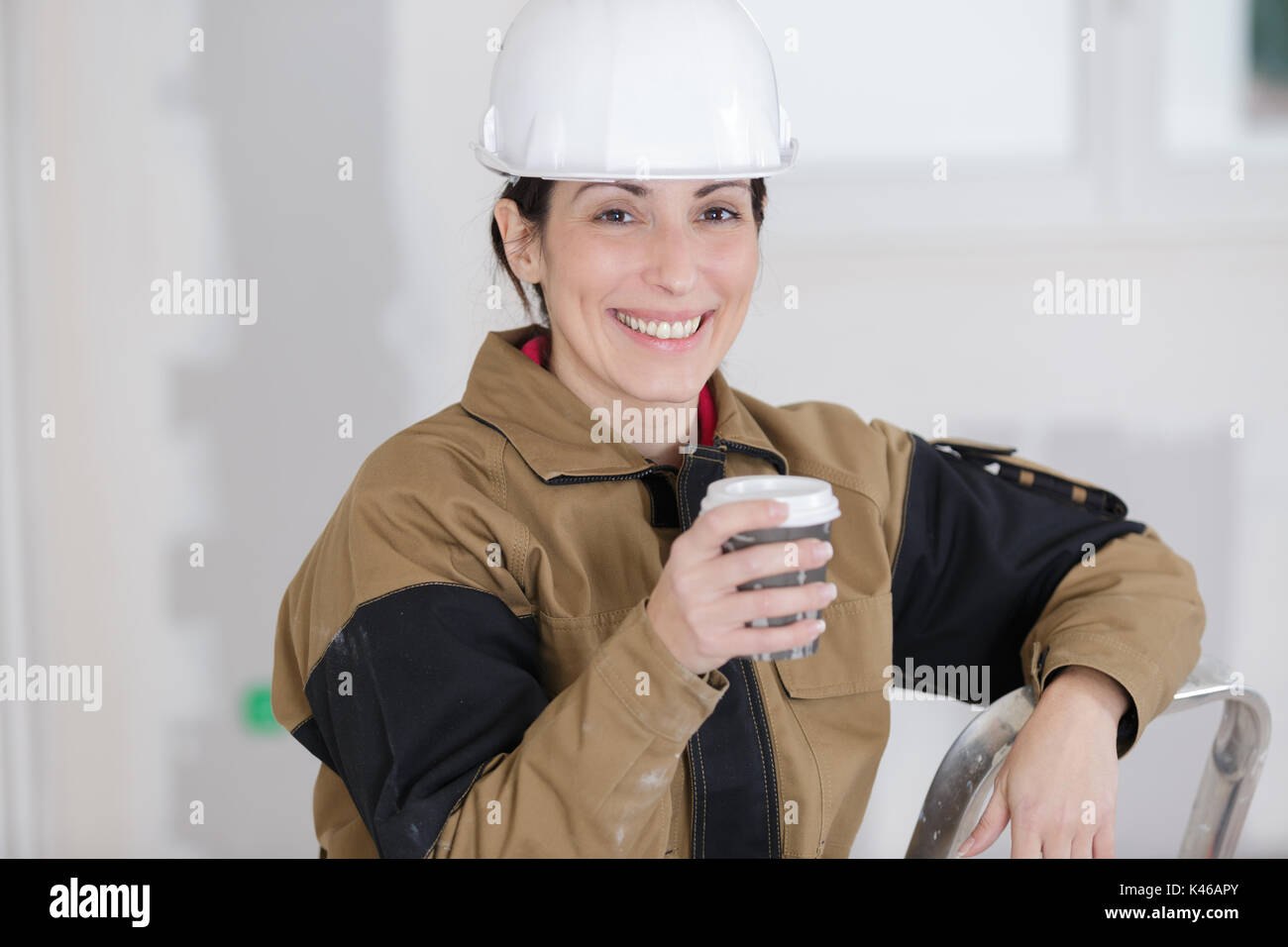 smiling female construction worker having a coffee break Stock Photo