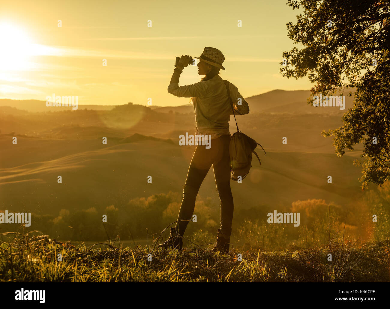 Discovering magical views of Tuscany. Full length portrait of adventure woman hiker with bag enjoying sunset in Tuscany while looking into the distanc Stock Photo