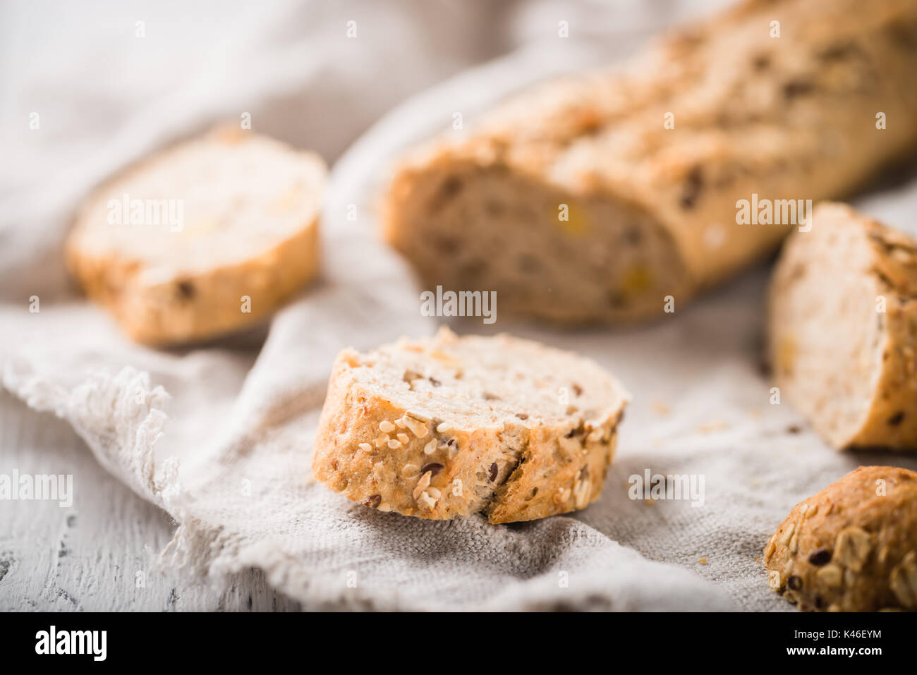 Fresh, healthy whole grain rye slices on cloth and rustic wooden table, baguette close up. Bakery and grocery concept Stock Photo