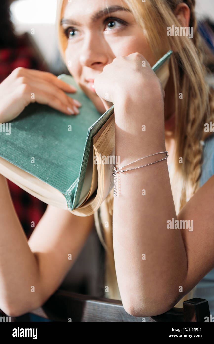 close up portrait of caucasian girl holding book and looking away Stock Photo