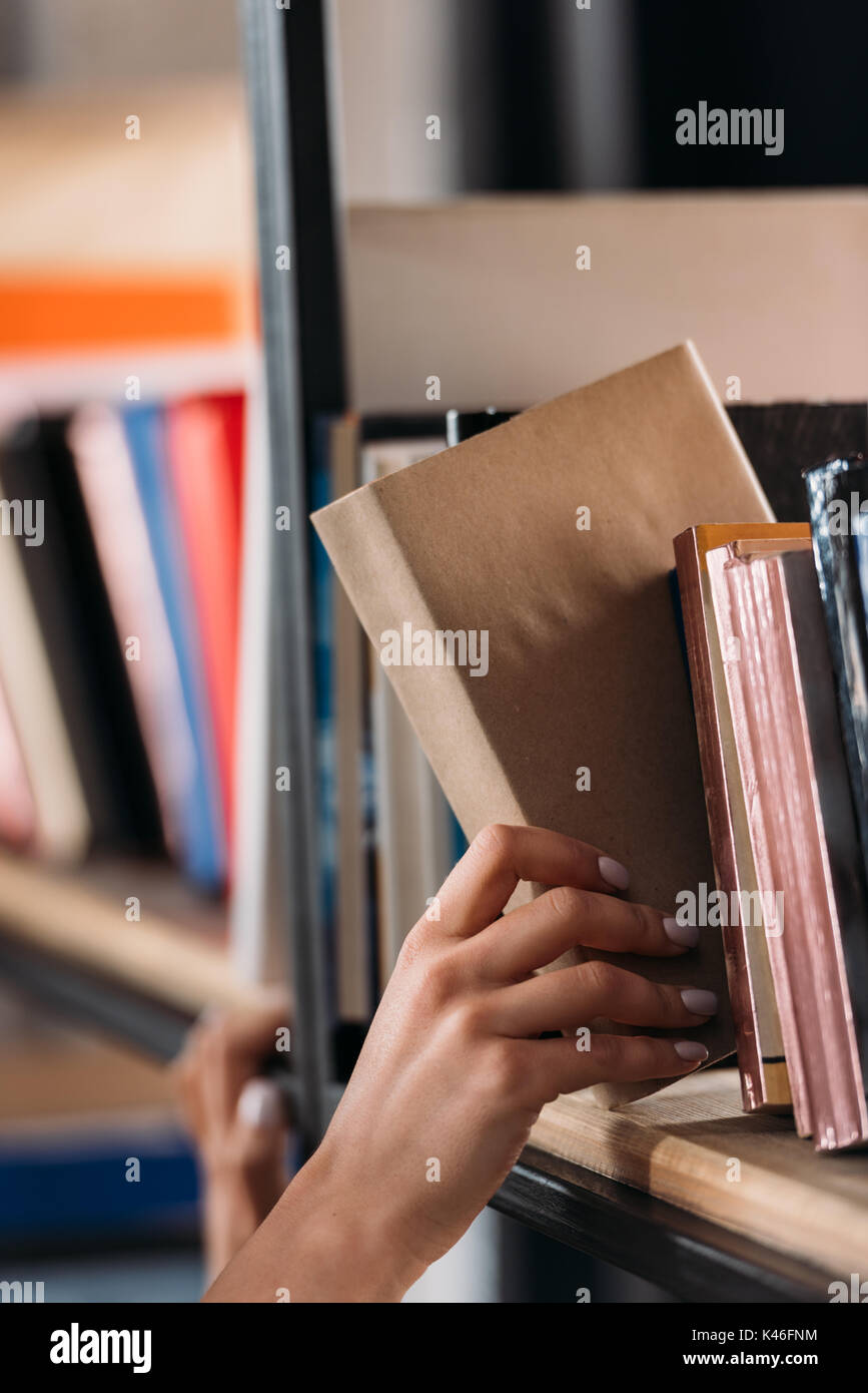 Cropped shot of student holding book at bookshelf in library Stock ...