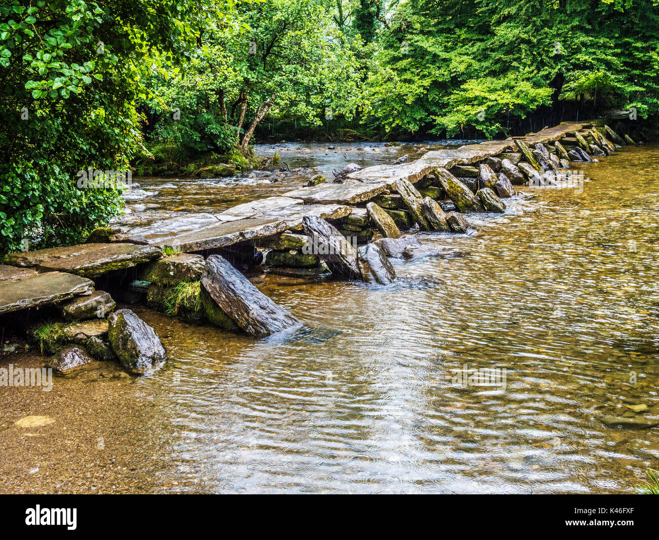 A rainy day at Tarr Steps, the famous 17-span medival clapper bridge across the River Barle in Exmoor, Somerset. Stock Photo