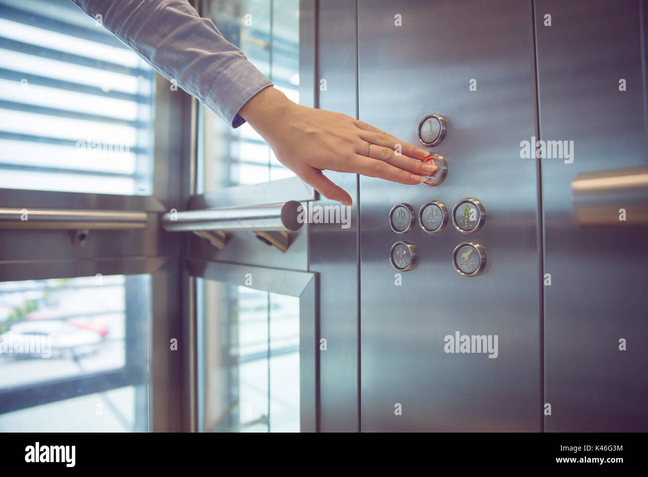 Close up on woman's hand pushing button in elevator. Stock Photo