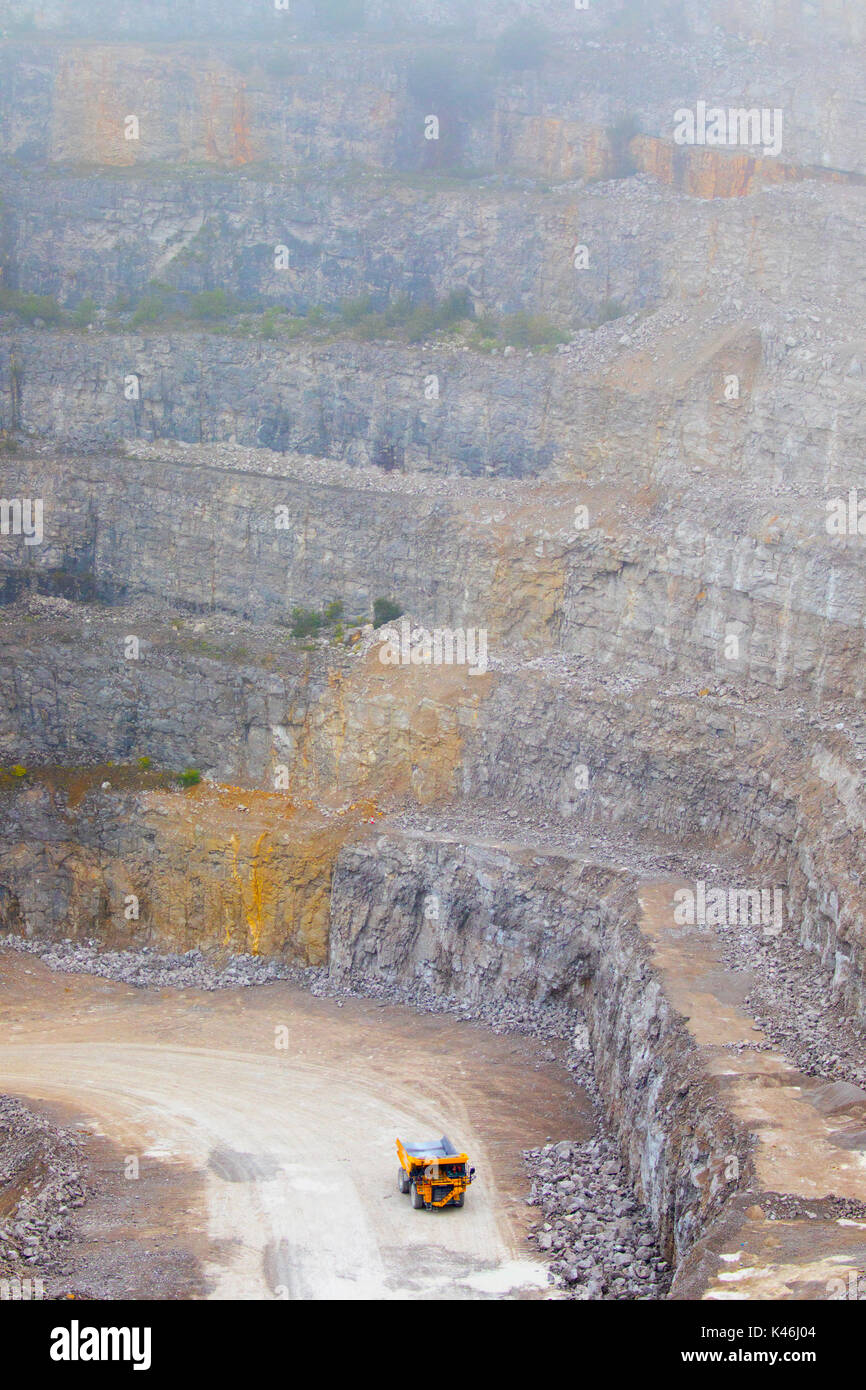 Quarry vehicle dwarfed by the shear expanse and size of Halkyn Quarry and Asphalt Plant pant-y-pwell Dwr, Halkyn, Flintshire, Wales, UK Stock Photo