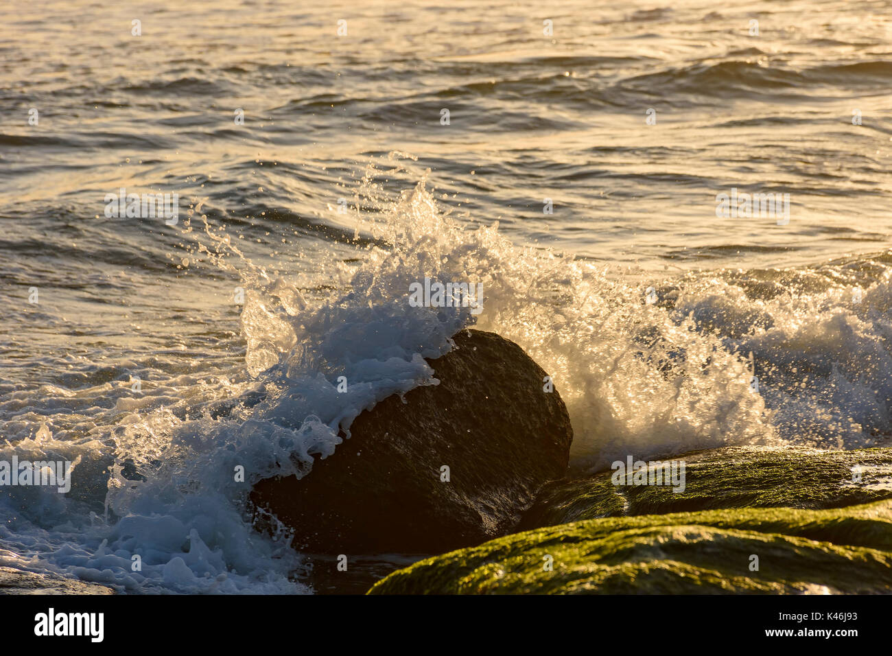 Sea water splashing over the stones on the beach Stock Photo - Alamy