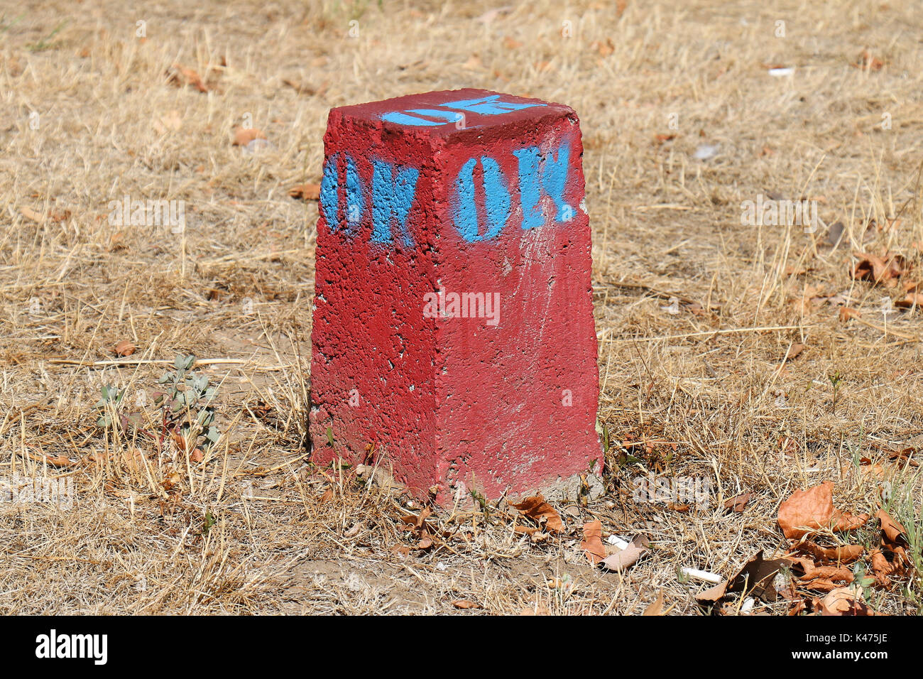 Red stone mark in dry grass field Stock Photo