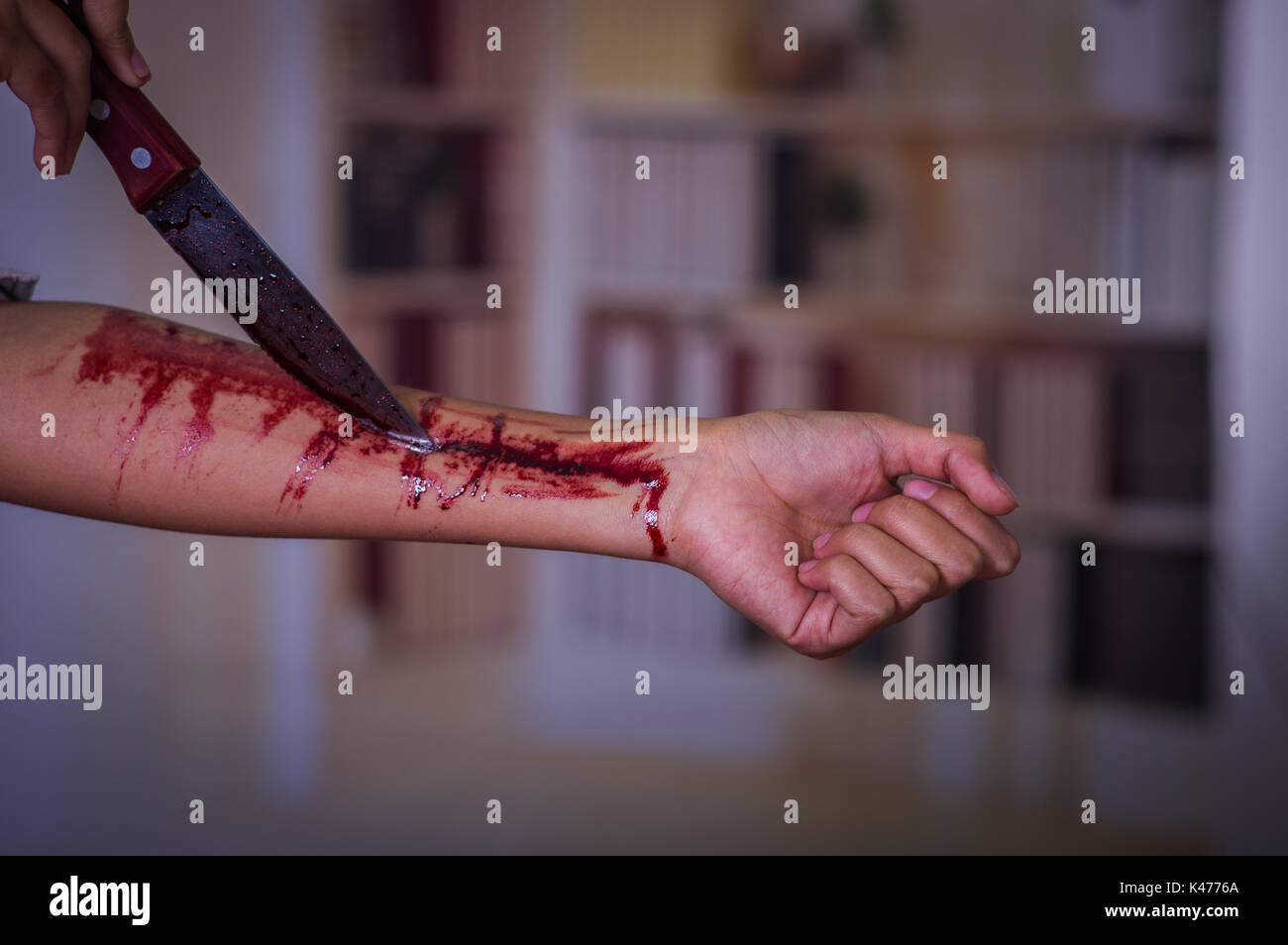 Close up of a young depressive woman holding a knife with her arm bleeding,  in a blurred background Stock Photo - Alamy