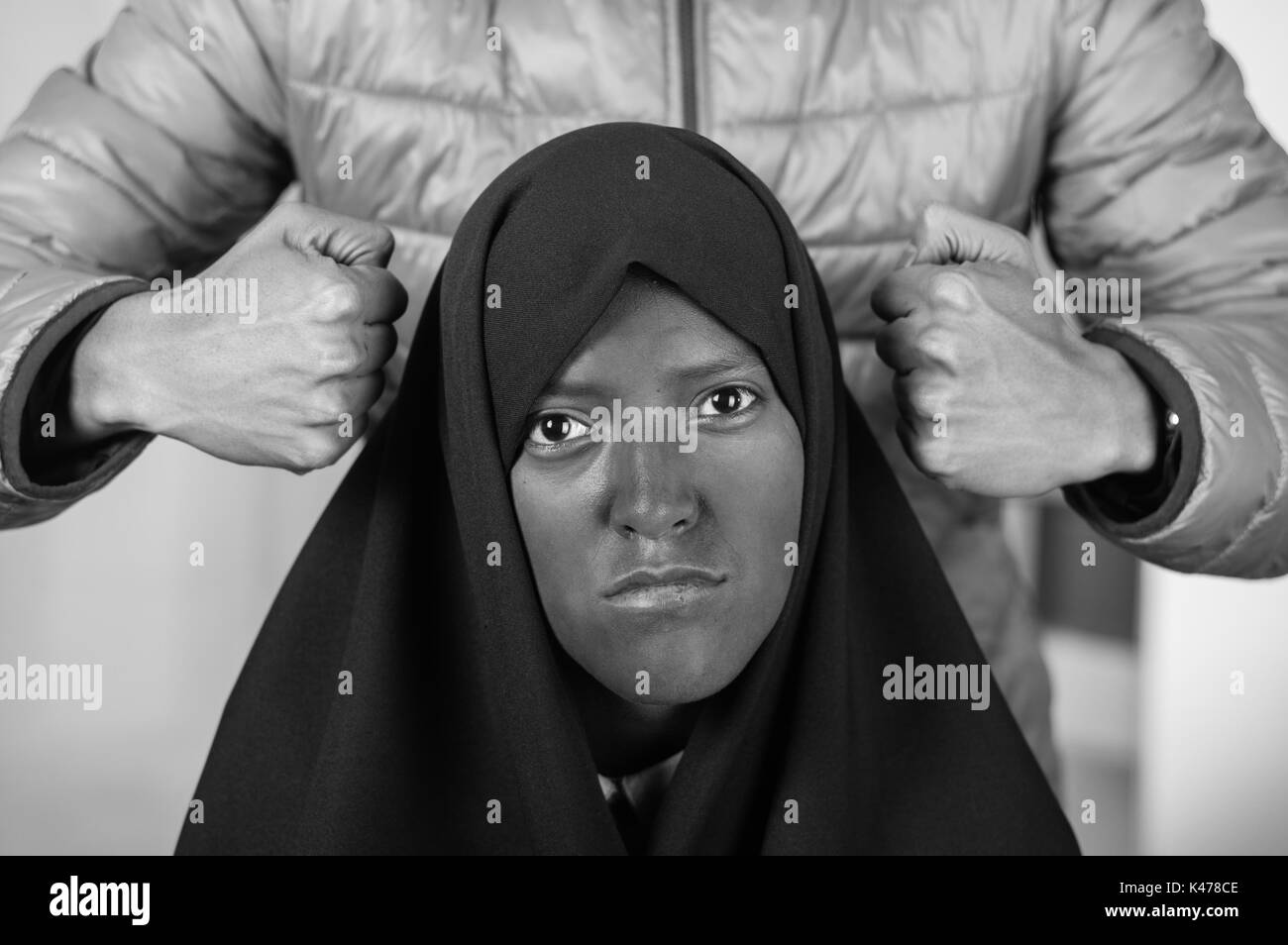 Portrait of a beautiful muslim girl wearing a hijab with a white man behind her