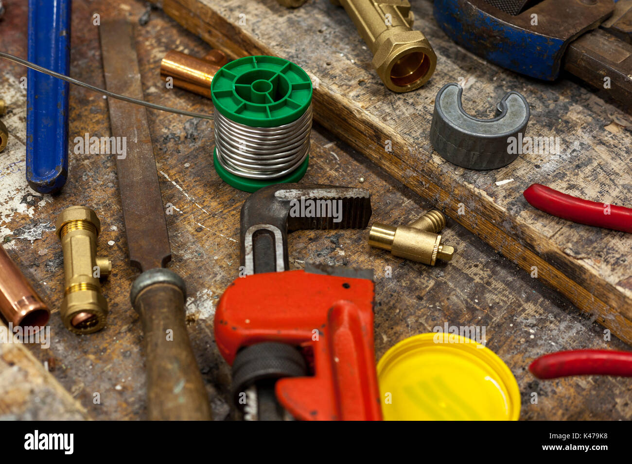 Open adjustable wrench and plumbing fittings on a work bench with a spool of lead free solder Stock Photo