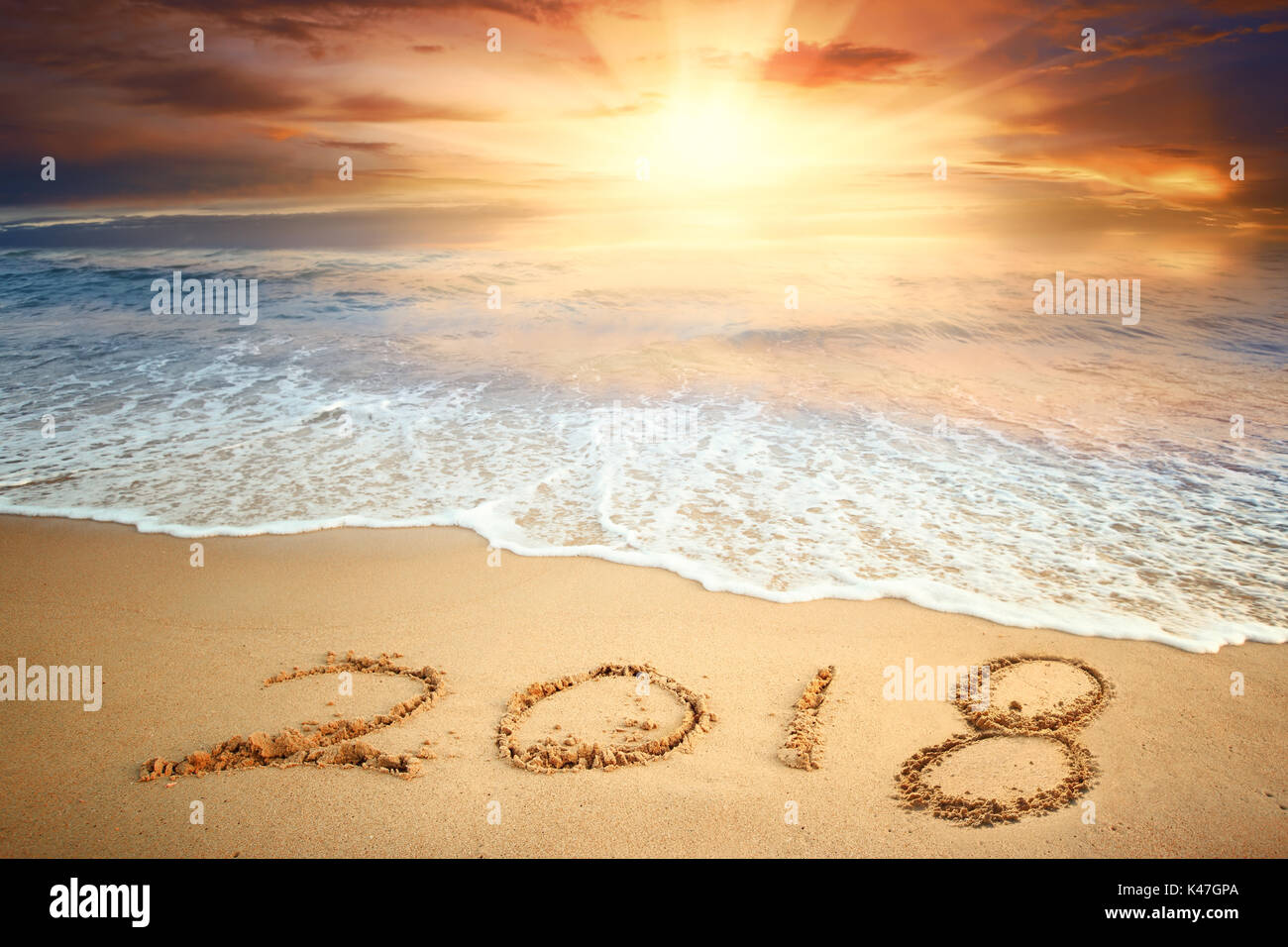 Year 2018 written on sand at sunrise Stock Photo