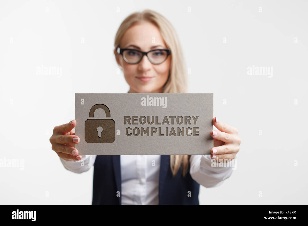 Business, Technology, Internet and network concept. Young woman holding a sign with an inscription REGULATORY COMPLIANCE Stock Photo