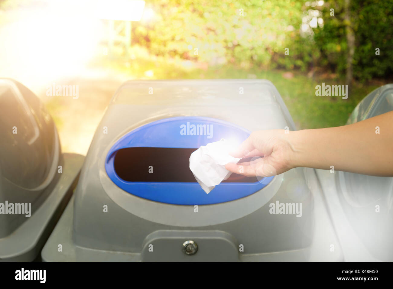 Hand throwing a white paper into recycling bin, environmental protection concept. Stock Photo