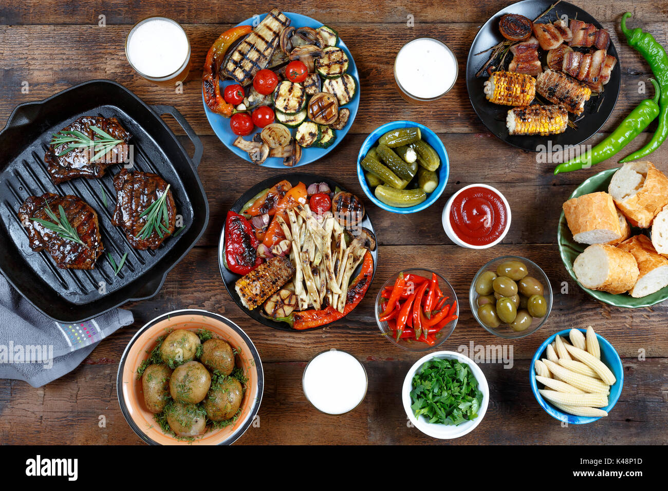 Dinner table with meat grill, bbq vegetables, salads, sauces, snacks and  beer, top view Stock Photo - Alamy