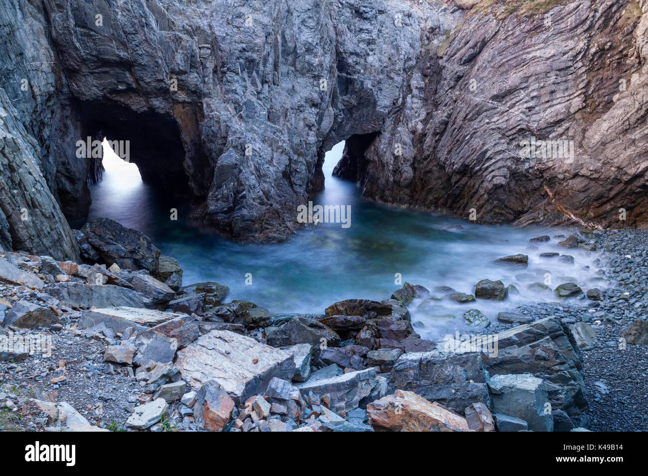 At the base of The Dungeon in The Dungeon Provincial Park are two sea arches at the bottom of a sink hole at sunrise in Newfoundland, Canada. Stock Photo