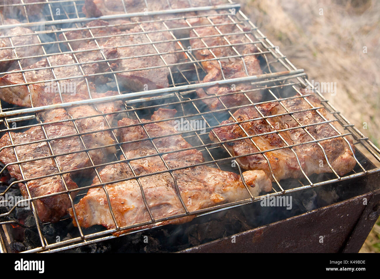 Juicy slices of meat cooking on an open flame grill. Roasted meat with
