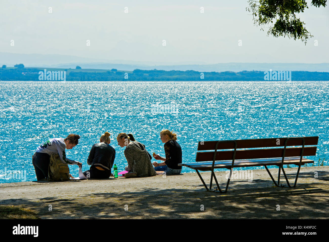 Young Women During The Lunch Break On The Shore Of Lake Neuchatel, Neuchatel, Switzerland Stock Photo