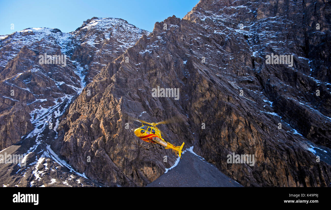 Helicopter Eurocopter As350 Ecureuil Against A Rock Face, Swiss Alps, Switzerland Stock Photo
