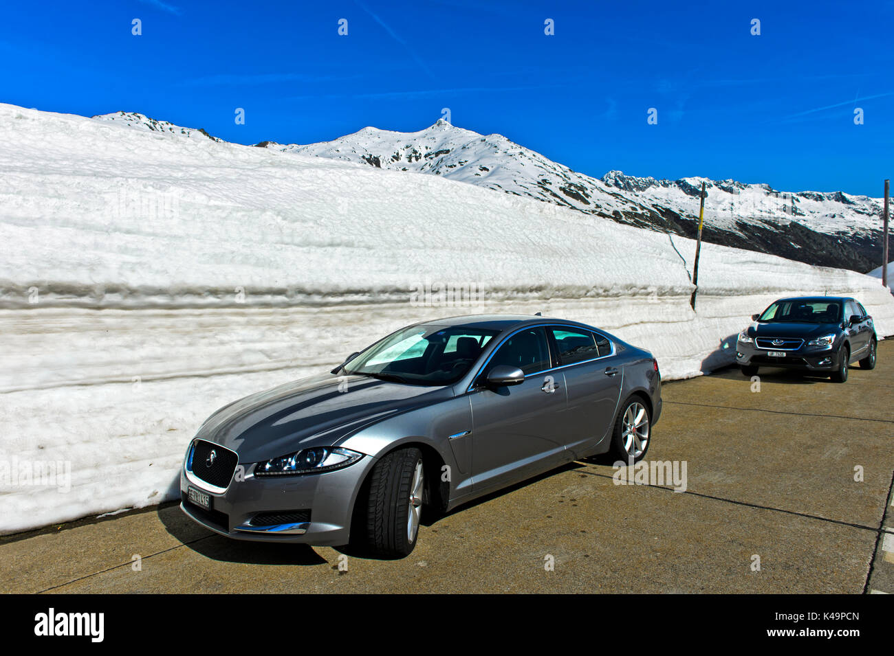 Cars Parking Next To A High Snow Wall On The St Gotthard Pass, Canton Of Ticino, Switzerland Stock Photo