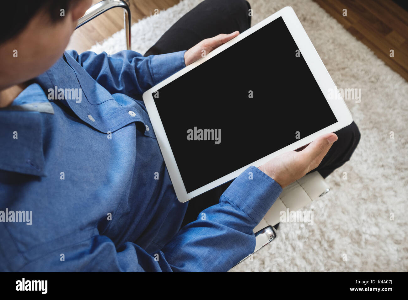 a man using digital tablet computer, sitting on modern chair, clipping path empty black vertical screen Stock Photo