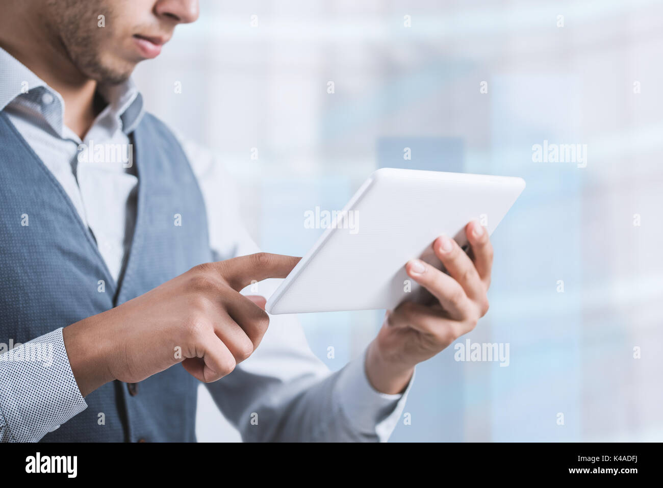 Thoughtful male person looking to the digital tablet screen, experienced entrepreneur reading some text or electronic book at the office. Stock Photo