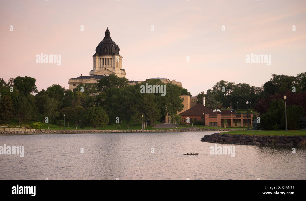 Water from the lake reflects the building in front of the capitol dome in Pierre, SD Stock Photo