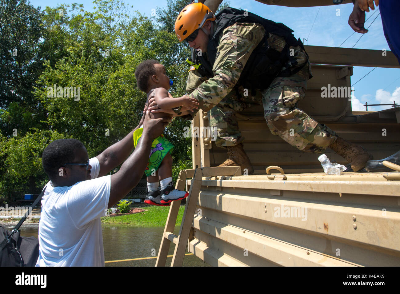 U.S. Army Spc. Gabriel Rangel lifts a small boy into a military truck for evacuation in the aftermath of Hurricane Harvey September 4, 2017 in Orange, Texas. Stock Photo