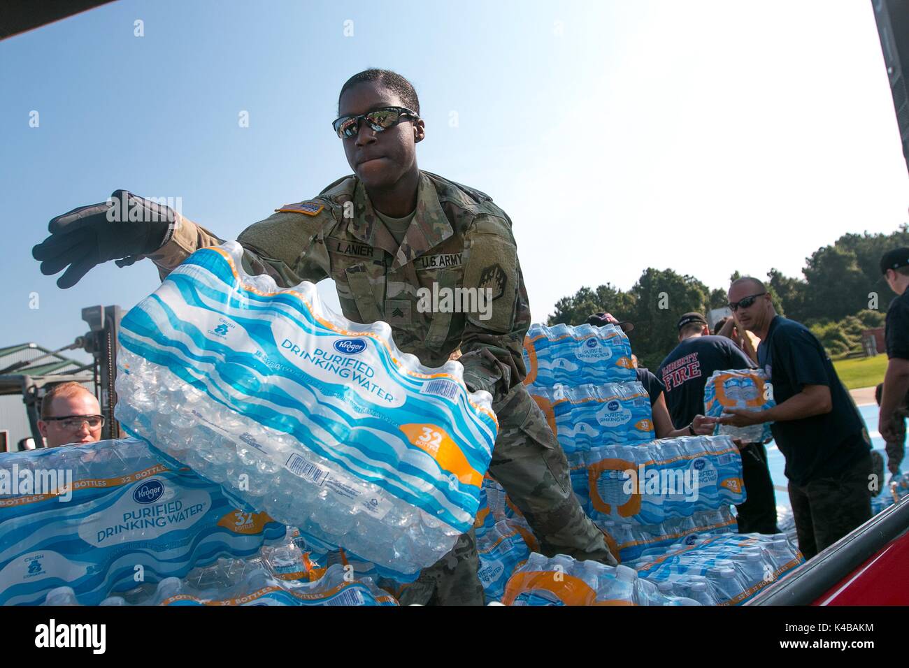 U.S Army Sgt. Samiera Lanier stacks cases of bottled water onto a Liberty Fire Department vehicle for delivery to residents in the aftermath of Hurricane Harvey September 2, 2017 in Liberty, Texas. Stock Photo